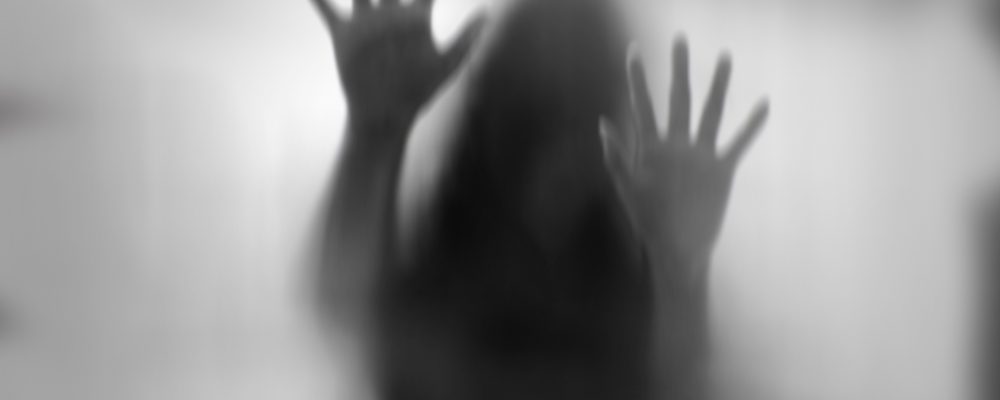 Horror woman behind the matte glass in black and white. Blurry hand and body figure abstraction